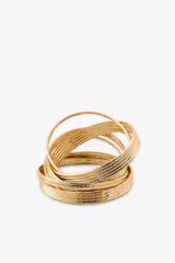 Pack de siete pulseras rígidas metálicas doradas con textura acanalada.