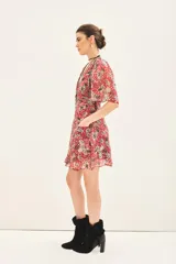 Vestido corto con estampado floral en tonos rojo y gris, escote en V, mangas cortas con volados, frunces en delantero y espalda, y bolsillos delanteros.