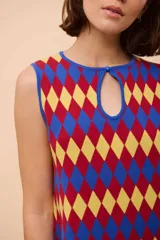 Vestido corto sin mangas con estampado de rombos en amarillo, azul y rojo. Tiene escote con abertura en forma de gota y ruedo con terminación en picos.