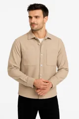 Sobrecamisa beige de corte recto, con cuello camisero, cierre frontal con botones a tono, mangas largas con puños abotonados, dos bolsillos de parche en el pecho y ruedo recto.