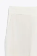 Pantalón de tiro alto color fucsia, con bolsillos delanteros y falsos bolsillos de vivo en la espalda. Tejido con efecto arrugado, pernera recta y cierre frontal con cremallera, botón interior y gancho.