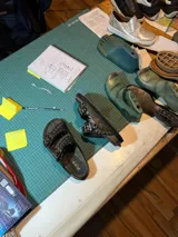 Sandalias de cuero color marrón con dos tiras anchas con hebillas metálicas y ojalillos.