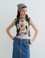 Musculosa corta con estampado de figura mitológica en tonos naranja, blanco y azul sobre fondo negro.