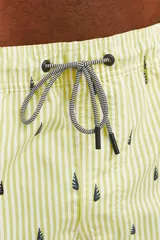 Short de baño amarillo con rayas verticales blancas y estampado de veleros en azul marino.