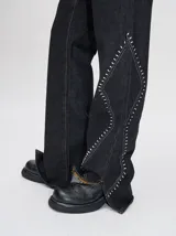 Pantalón de jean azul de tiro alto y corte oxford con apliques metálicos en bolsillos y laterales.