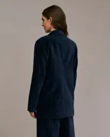 Blazer azul con finas rayas verticales, de corte cruzado con un botón, hombreras y bolsillos con solapa.