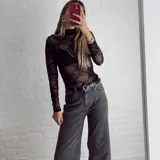 Top de encaje negro con cuello alto y mangas largas.