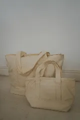 Bolso tote pequeño de lona color crudo con doble asa corta. Decorado con parches termoadhesivos de gafas de sol, inicial con corona, cóctel y cangrejo.