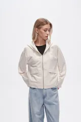 Campera color crudo de lino con capucha, cierre frontal y bolsillos plaqué.