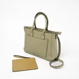 Cartera tipo tote de cuero sintético color verde con doble asa de mano y correa larga desmontable. Tiene un bolsillo frontal con cierre y detalle de tira decorativa.
