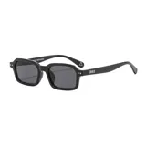 Gafas de sol unisex con montura cuadrada negra y lentes grises. Patillas transparentes con detalle de remaches plateados. Incluye estuche.