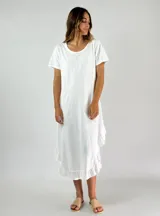 Vestido blanco de corte recto, largo midi, con cuello redondo y mangas cortas. Presenta volados en el ruedo.