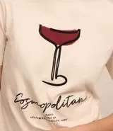 Remera de algodón color crema con cuello redondo y mangas cortas. Estampa frontal de una copa de Cosmopolitan y la inscripción "Cosmopolitan".