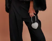 Clutch de mano en forma de corazón, cubierto de strass plateados. Incluye asa corta de cadena plateada.