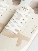 Zapatillas de diseño retro en color beige con detalles en azul, parte superior de ante y cuero, y suela de goma.