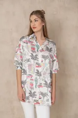 Camisa larga estampada con diseño de palmeras y elementos gráficos, de manga larga y corte holgado.