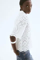 Camisa blanca de algodón con broderie, corte holgado, cuello abierto, mangas anchas al codo y ribete festoneado en mangas y bajo.