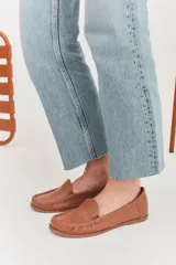 Mocasines de cuero color marrón claro con costuras a la vista.