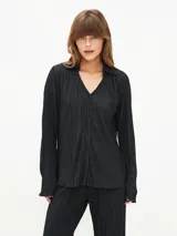 Camisa negra con textura plisada, cuello clásico, escote en V y mangas largas.