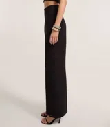 Pantalón de vestir negro, de corte palazzo, sin cintura, con pliegues y cierre trasero.