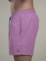 Short de baño verde con estampado de margaritas blancas y cordón ajustable naranja.