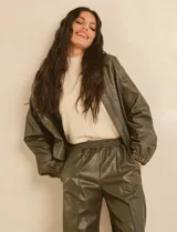 Campera bomber de cuero sintético negra con mangas color beige, cuello clásico y cierre frontal con cremallera.