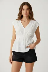 Blusa blanca de algodón con bordado floral, escote en V y corte holgado.