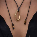 Collar con dije irregular dorado y cordón marrón ajustable.