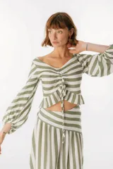 Blusa blanca de lino con escote en V, mangas largas abullonadas y frunce central.