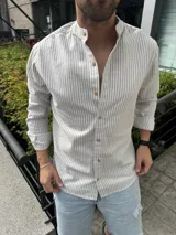 Camisa de manga larga con cuello mao y cierre frontal con botones de madera. Diseño a rayas verticales en tonos beige y gris.
