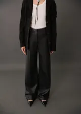 Pantalón negro con efecto piel, diseño wide leg, tiro medio y cierre oculto.