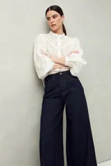 Pantalón de jean negro de calce ultra wide leg, tiro alto y silueta amplia desde la cadera hasta el bajo. Diseño clásico de cinco bolsillos y cierre con botón metálico y cremallera.