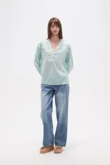 Blusa de algodón color menta, con escote en V, mangas largas y detalles de bordado floral y mostacillas en los hombros y el escote.