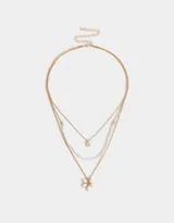 Collar corto multicadena dorada con una cadena de eslabones, una de perlas y una de eslabones con dije de flor blanca.