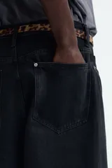 Pantalón de jean negro de corte holgado, con tiro bajo y cinco bolsillos.