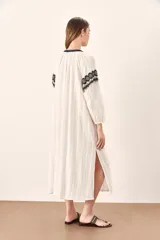 Túnica blanca de algodón con bordados geométricos en negro y dorado en el cuello, el frente y los puños.