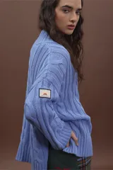 Sweater de punto trenzado color gris claro, con cuello alto y mangas largas.