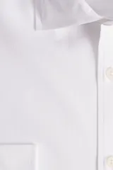 Camisa blanca de manga larga texturizada, tejida en dobby, con cuello italiano y cartera abotonada. Tiene un logo bordado en el pecho.