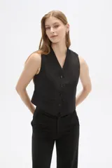 Chaleco negro sin mangas con escote en V y cierre frontal con botones. Diseño corto con solapas simuladas a la altura de la cintura.