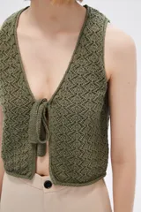 Top sin mangas de algodón color blanco, tejido al crochet, con escote en V profundo y lazo de ajuste en el frente.