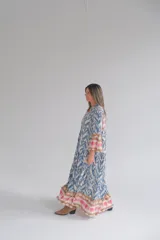 Vestido largo celeste con estampado abstracto en tonos azules, marrones y rosados. Tiene cuello mao, mangas 3/4 acampanadas y cierre frontal con botones.