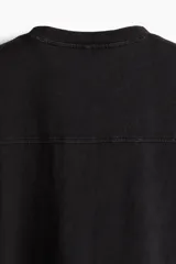 Musculosa deportiva negra sin mangas de punto suave con efecto lavado, corte holgado, cuello redondo ribeteado, bajo recto con aberturas laterales cortas y sisas sin rematar.