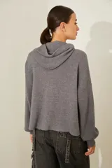 Campera de punto gris con capucha y cierre, de corte holgado y bolsillos frontales.