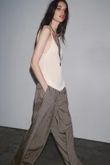 Pantalón de tiro medio con cintura elástica y bolsillos laterales ocultos en costura. Pierna ancha y diseño a rayas verticales azules y blancas.