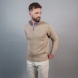 Buzo color beige de algodón y poliéster, con cuello alto y cierre metálico a la mitad del pecho.