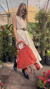 Mochila bandolera color marrón con herrajes color peltre. Tiene un compartimento principal amplio con cierre, un bolsillo frontal con cierre y dos bolsillos laterales abiertos. Incluye correa ajustable para usar al hombro o cruzada.