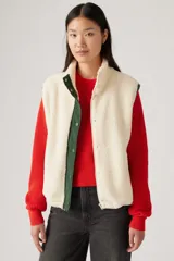 Chaleco color crema de sherpa con cuello alto, cierre frontal con cremallera y ribete de contraste en verde.