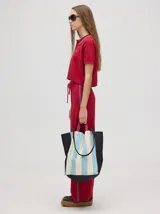 Pantalón de algodón negro, corte holgado y pierna ancha con pretina elástica. Presenta rayas bicolor al costado en blanco y celeste. Calce de tiro alto.