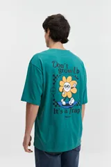 Remera de manga corta color salmón, de corte holgado con estampado en la espalda que incluye una flor con cara y texto.