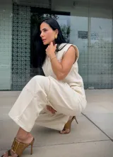 Camisa sin mangas color off-white, con cuello camisero, cierre frontal de botones y dos bolsillos de parche en el pecho.